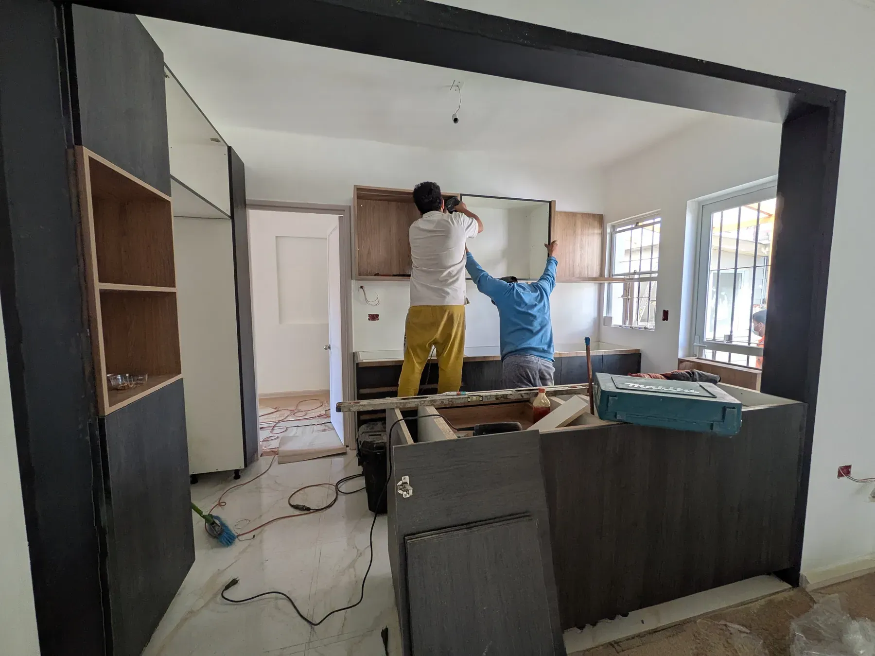 Dos maestros montando los muebles superiores de la cocina a medida